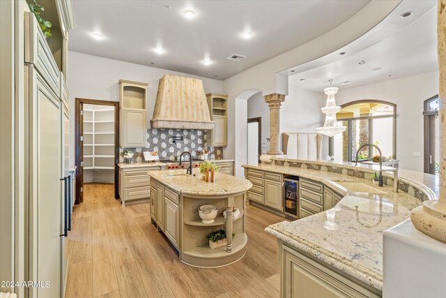 kitchen featuring light wood finished floors, visible vents, paneled built in refrigerator, open shelves, and a sink