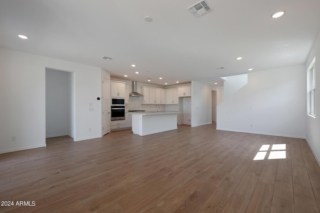 unfurnished living room featuring sink and light hardwood / wood-style flooring