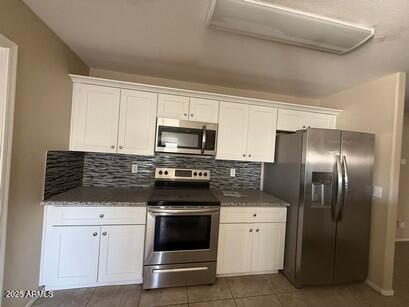 990 E Desert Rose Trl, San Tan Valley, AZ 85143 - kitchen with stainless steel appliances, white cabinets, decorative backsplash, and tile patterned flooring