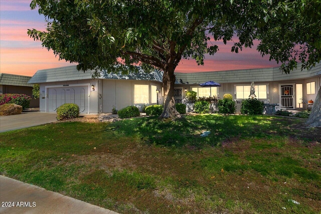 ranch-style home featuring a lawn and a garage