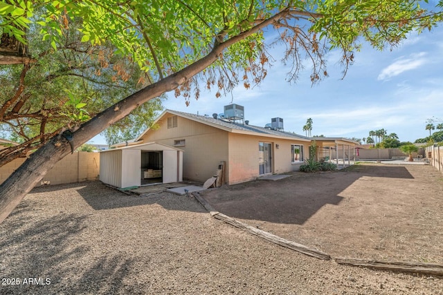 back of house with an outbuilding, a storage unit, a fenced backyard, and a patio area