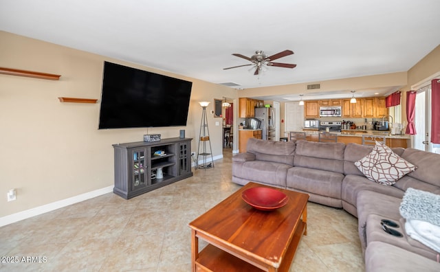 living room with light tile patterned flooring, visible vents, baseboards, and ceiling fan