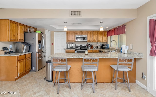 kitchen featuring visible vents, a peninsula, stainless steel appliances, a raised ceiling, and a sink