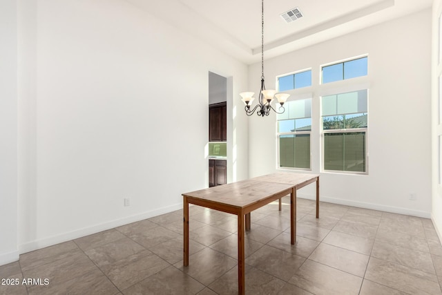 unfurnished dining area featuring light tile patterned flooring, a chandelier, a raised ceiling, and a high ceiling