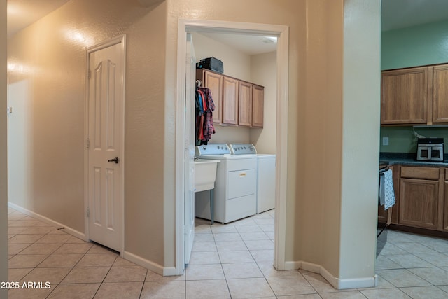 laundry area with baseboards, light tile patterned floors, and washer and dryer