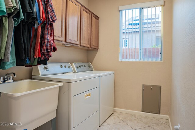 clothes washing area with a sink, cabinet space, washing machine and clothes dryer, light tile patterned flooring, and baseboards