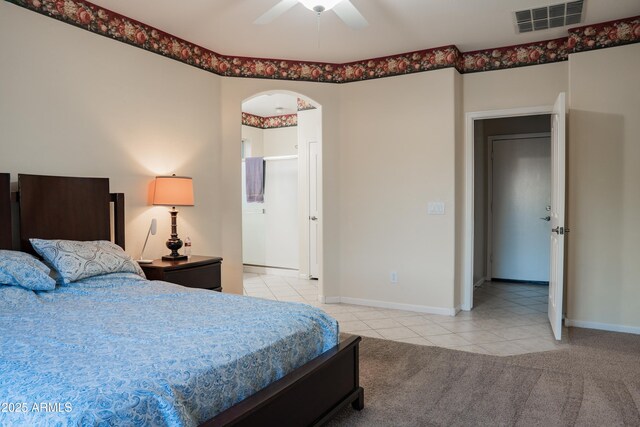 bedroom featuring light tile patterned floors, light colored carpet, visible vents, baseboards, and arched walkways
