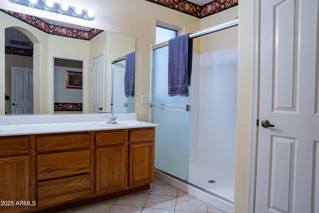 bathroom with tile patterned floors, a shower stall, double vanity, a sink, and visible vents