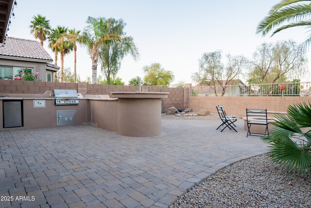 view of patio with fence, area for grilling, and an outdoor kitchen