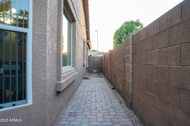 view of side of property with a patio, stucco siding, and fence
