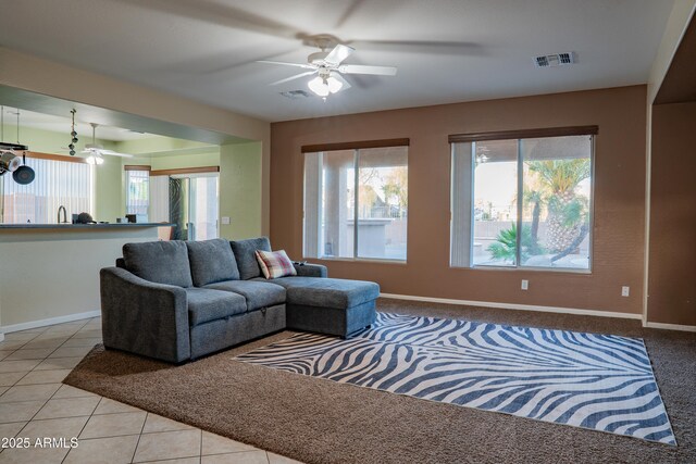 living area with baseboards, visible vents, tile patterned floors, and ceiling fan