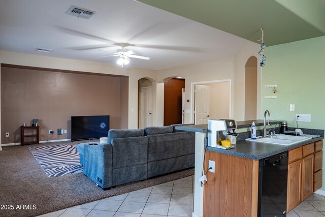 kitchen featuring arched walkways, dark countertops, dishwasher, a sink, and visible vents