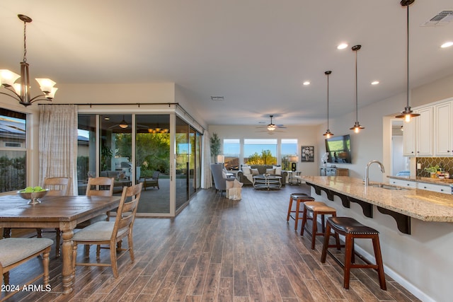 dining area with sink, dark hardwood / wood-style floors, and ceiling fan with notable chandelier