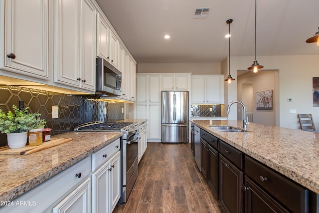 kitchen with white cabinets, dark wood-type flooring, sink, decorative light fixtures, and stainless steel appliances