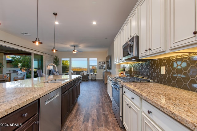 kitchen featuring dark wood-type flooring, sink, decorative light fixtures, white cabinetry, and appliances with stainless steel finishes