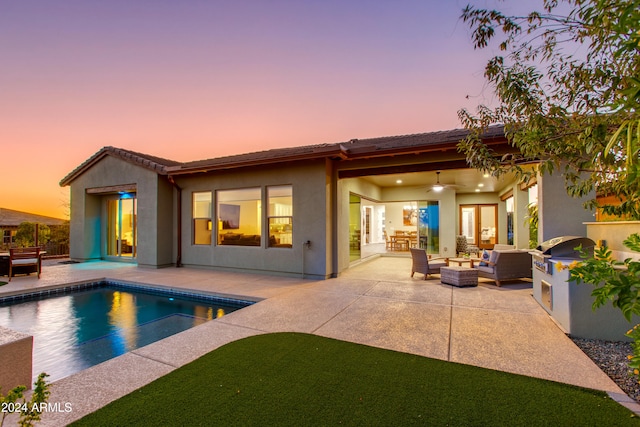 back house at dusk with an outdoor living space and a patio area