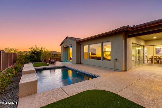 pool at dusk featuring a patio