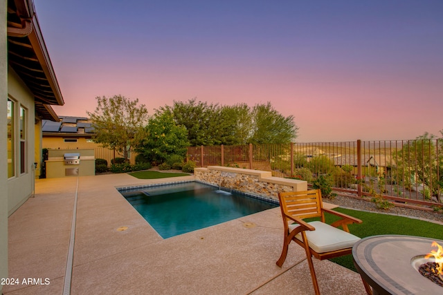 pool at dusk with an outdoor fire pit, a patio area, and pool water feature