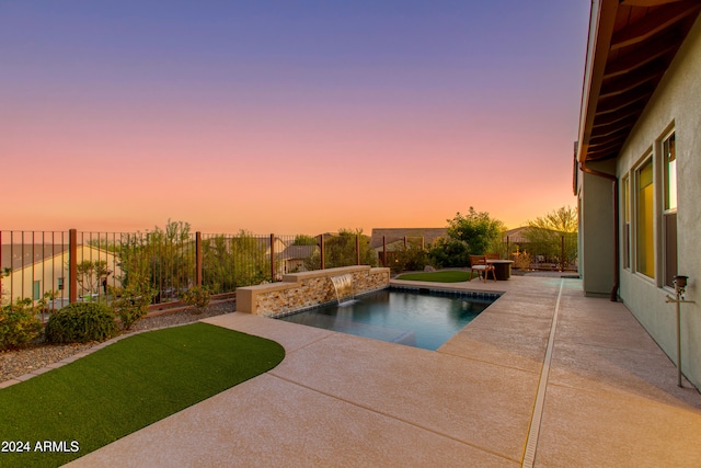 pool at dusk featuring pool water feature and a patio area