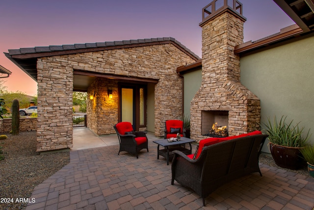 patio terrace at dusk with an outdoor living space with a fireplace