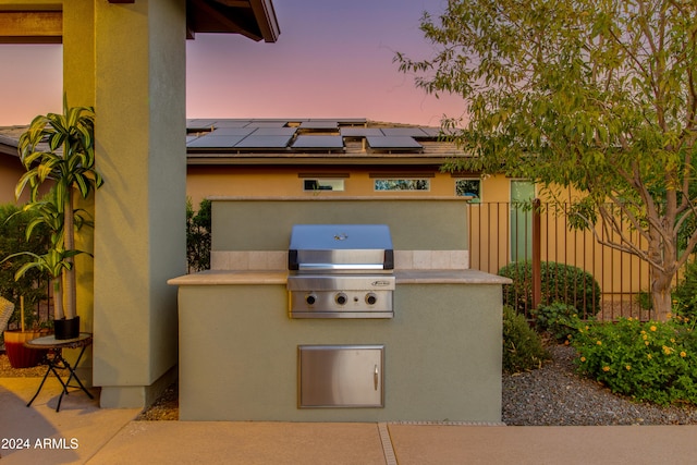 patio terrace at dusk featuring exterior kitchen and grilling area