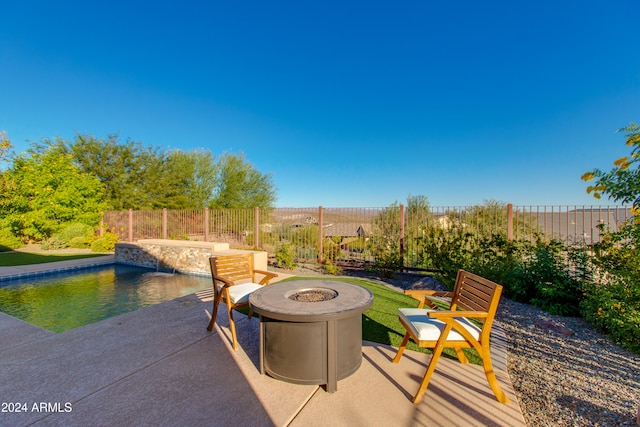 view of patio featuring a fenced in pool, a fire pit, and pool water feature