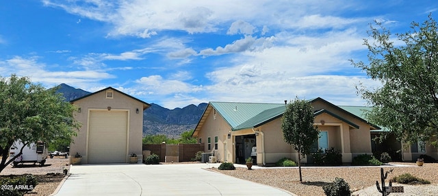 view of front facade featuring stucco siding, a mountain view, metal roof, and fence