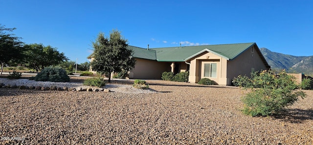 view of front of property featuring stucco siding, a mountain view, and metal roof