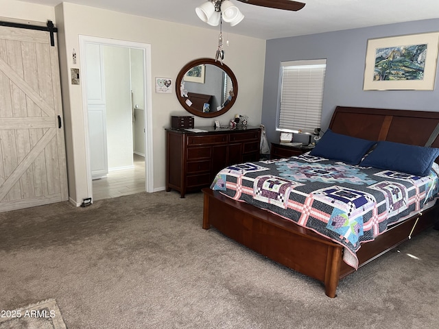 bedroom with ceiling fan, carpet, and a barn door