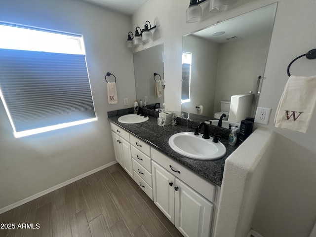 bathroom with a sink, baseboards, toilet, and wood finished floors