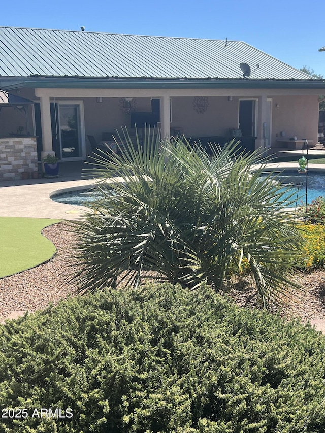 rear view of property with a patio, stucco siding, and metal roof