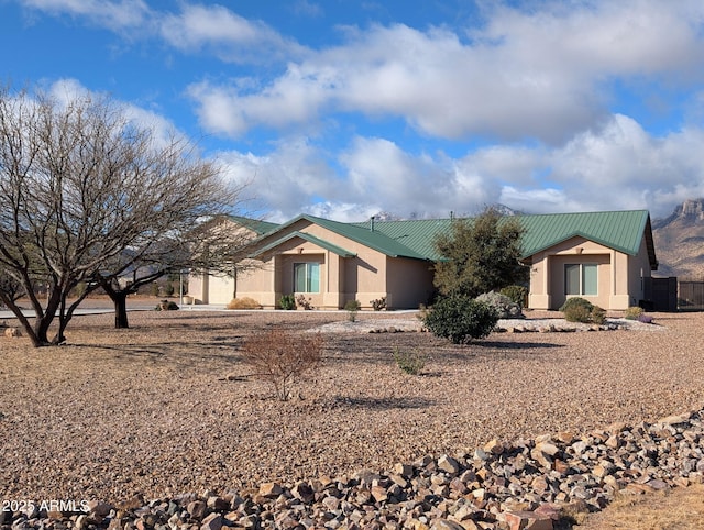 view of front of house with stucco siding and metal roof