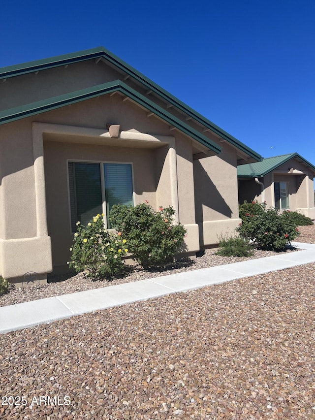 view of side of property featuring stucco siding and metal roof