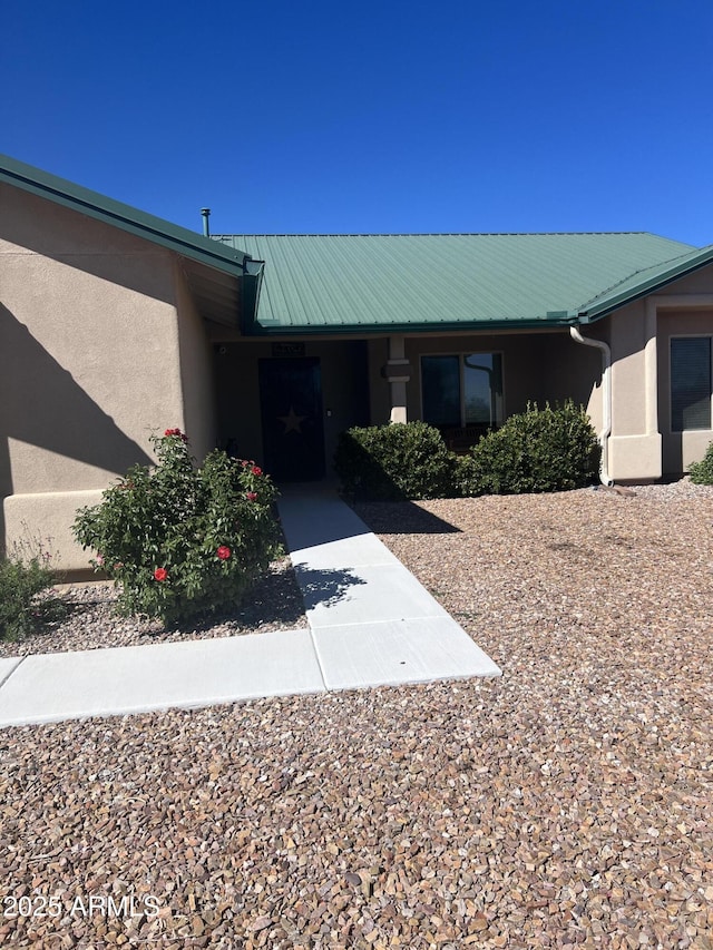 doorway to property featuring stucco siding and metal roof