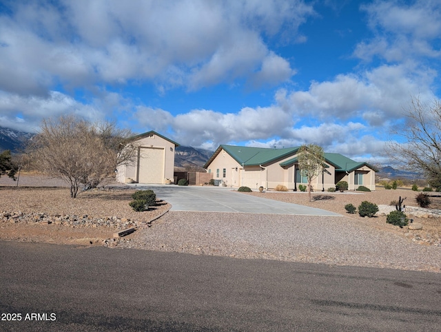 view of front of house with concrete driveway, a storage unit, and an outdoor structure