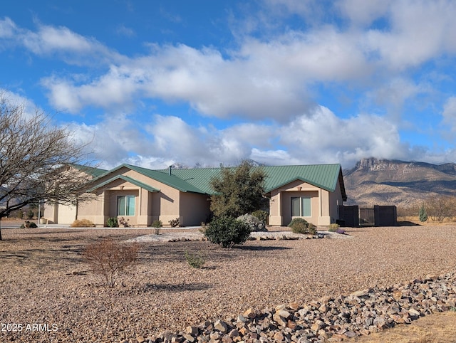 ranch-style house with stucco siding, metal roof, and fence