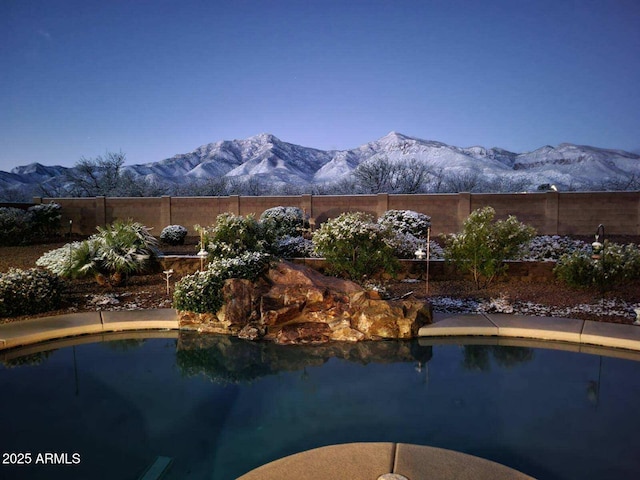 view of swimming pool with a mountain view, a fenced in pool, and fence