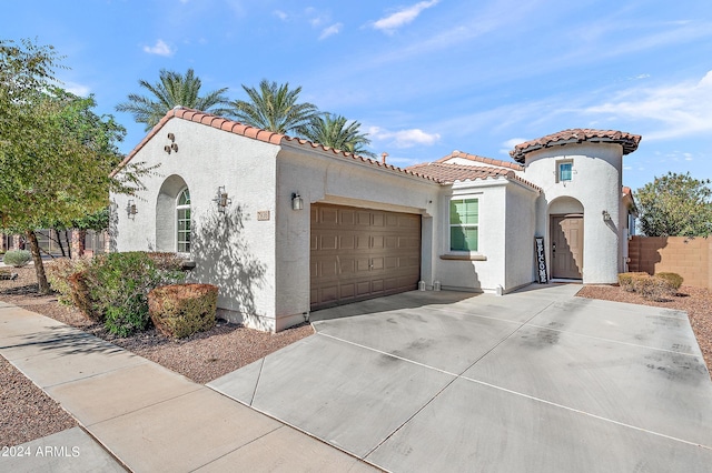 mediterranean / spanish house with driveway, an attached garage, a tiled roof, and stucco siding