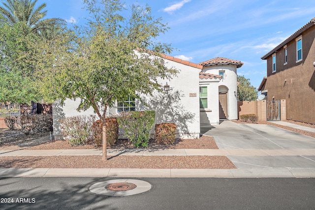 mediterranean / spanish-style home featuring a tile roof, stucco siding, a gate, and fence