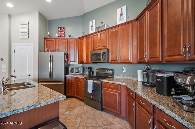 kitchen featuring light stone countertops, light tile patterned floors, appliances with stainless steel finishes, brown cabinets, and a sink