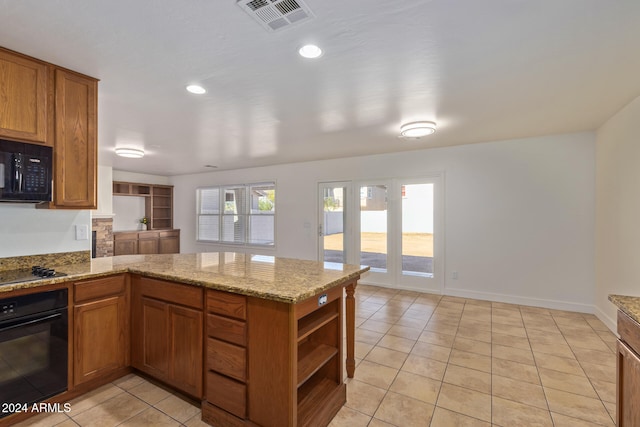 kitchen featuring kitchen peninsula, light stone counters, light tile patterned floors, and black appliances