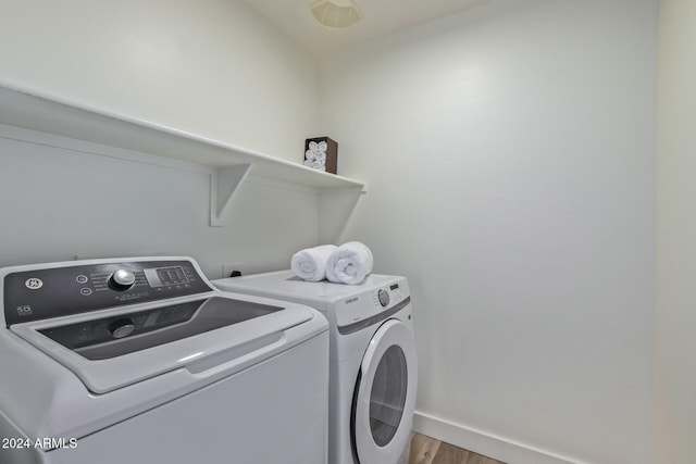 clothes washing area featuring washer and dryer and wood-type flooring