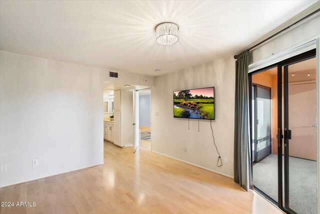 spare room with a notable chandelier and light hardwood / wood-style flooring