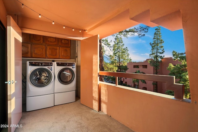 laundry area featuring washing machine and clothes dryer, cabinets, and light colored carpet