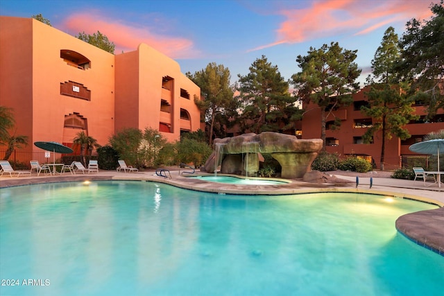 pool at dusk featuring a community hot tub