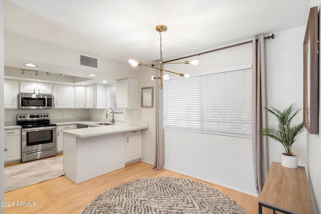 kitchen with stainless steel appliances, sink, light hardwood / wood-style flooring, a notable chandelier, and white cabinetry