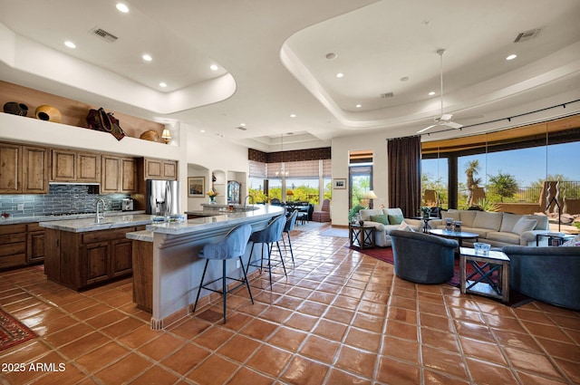 8154 E Tecolote Cir, Scottsdale, AZ 85266 - kitchen with a large island with sink, stainless steel refrigerator with ice dispenser, a tray ceiling, open floor plan, and brown cabinets