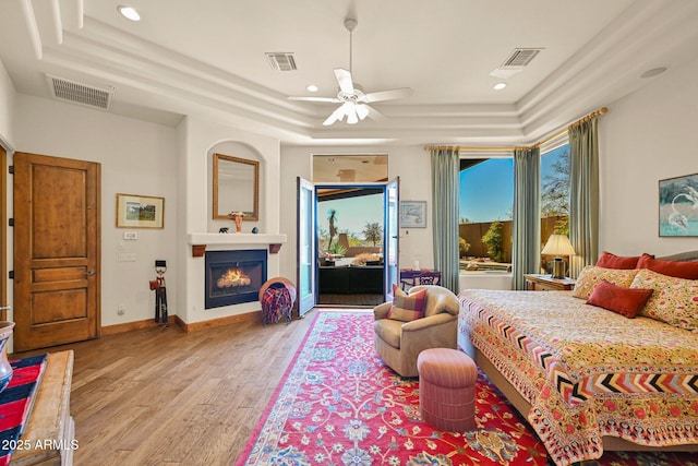 8154 E Tecolote Cir, Scottsdale, AZ 85266 - bedroom featuring a tray ceiling, wood finished floors, recessed lighting, access to exterior, and a warm lit fireplace