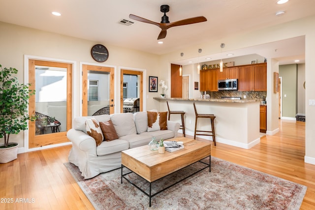 living room featuring ceiling fan and light hardwood / wood-style floors