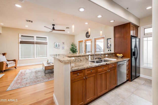 kitchen featuring sink, black fridge, light stone counters, kitchen peninsula, and dishwasher